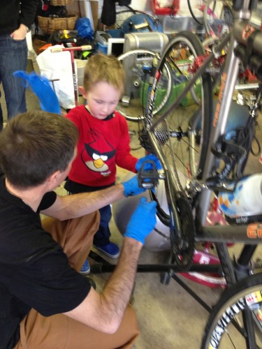 Pascal was helping his dad put a new chain on his bike.  He made sure he had gloves on too.